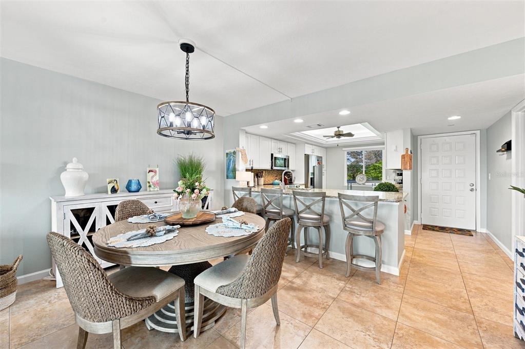 A dining area with a round table and chairs opens to a kitchen with bar seating — 9604 CORTEZ ROAD W UNIT 422, BRADENTON, FL