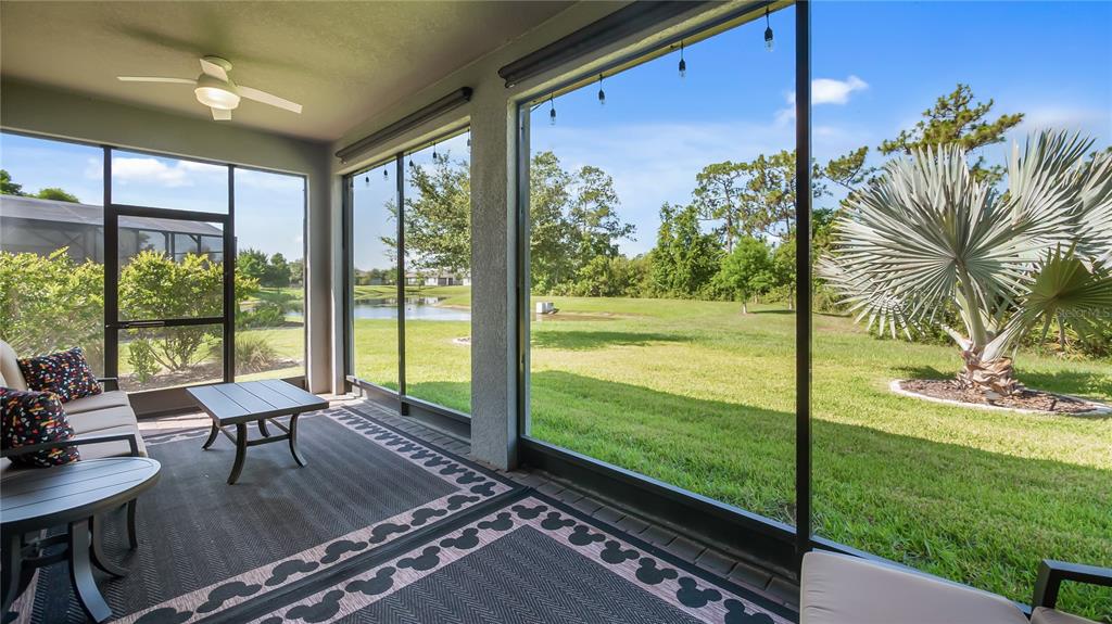 A screened-in patio features a ceiling fan, outdoor furniture, and views of a grassy yard — 3899 WINGED ELM COURT, CLERMONT, FL