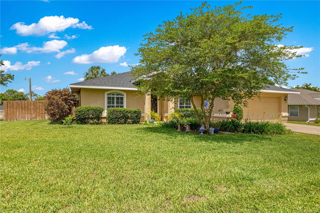 A single-story house with a tan exterior, a large front tree, and a green lawn — 2208 SE 24TH TERRACE, OCALA, FL