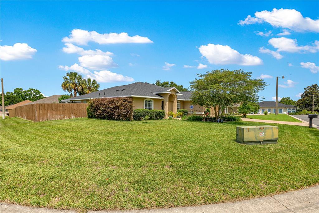 A single-story house with a tan exterior, dark roof, and a large front lawn — 2208 SE 24TH TERRACE, OCALA, FL