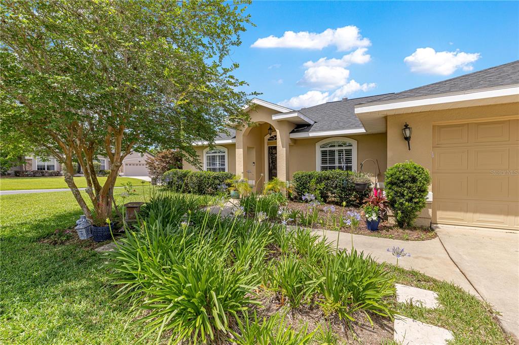 The exterior of a single-story tan house features a front garden and a garage — 2208 SE 24TH TERRACE, OCALA, FL