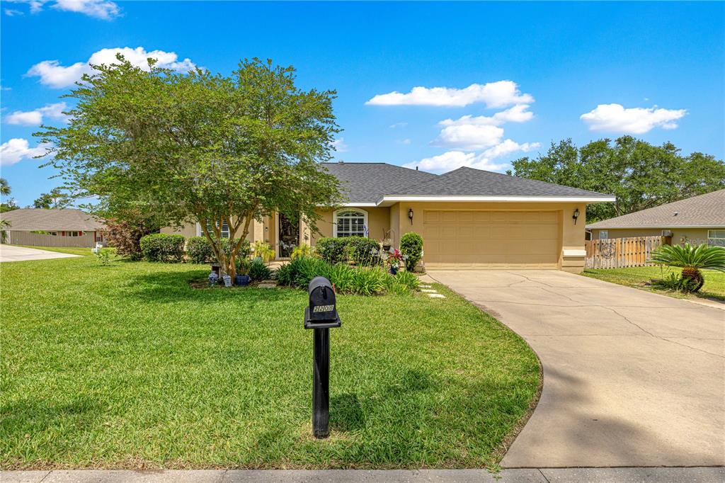 A single-story house with a tan exterior, a two-car garage, and a large front tree — 2208 SE 24TH TERRACE, OCALA, FL