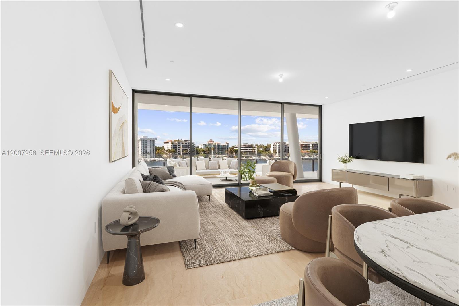 A modern living room features a large sectional sofa, marble coffee table, and waterfront balcony — 5 Grove Isle Dr # S401, Miami FL 33133, MIAMI, FL