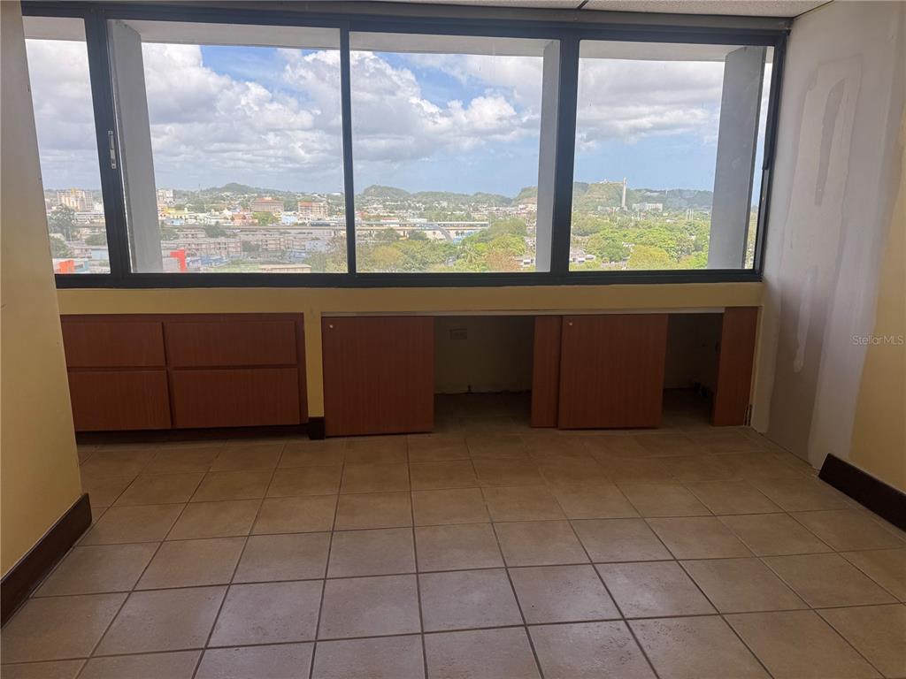 An interior room with tile flooring, built-in wooden cabinets, and large windows overlooking a city — Cond Torre San Pablo SANTA CRUZ UNIT 805, BAYAMON, PR