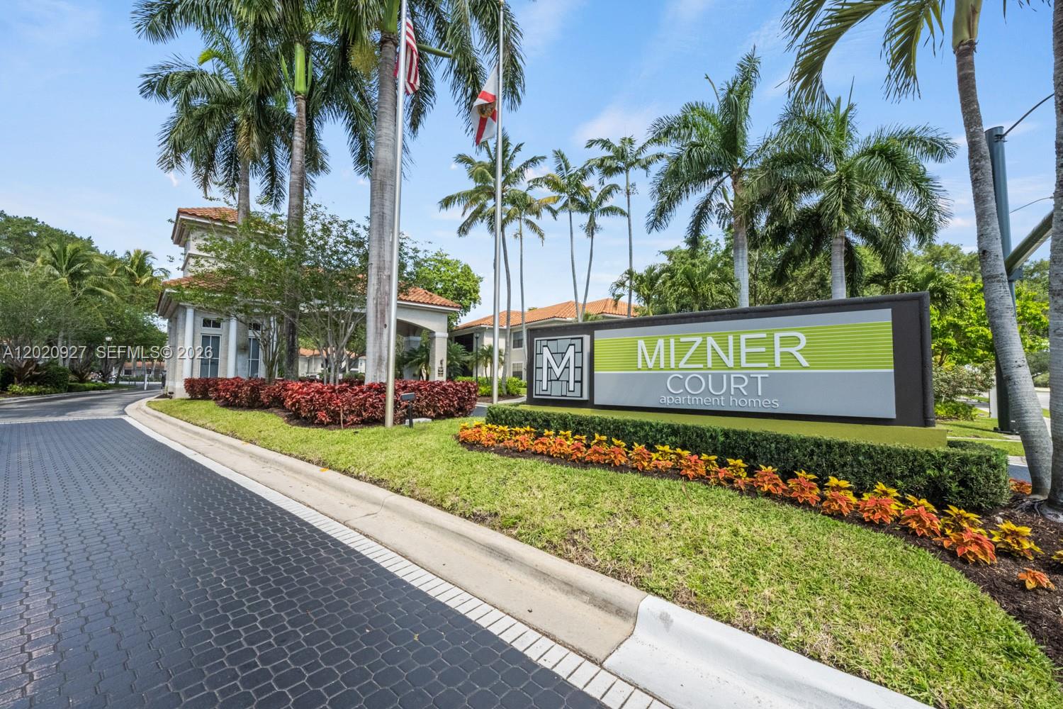 The exterior entrance of Mizner Court apartment homes features a sign, landscaping, and palm trees — 6503 N Military Trl, Boca Raton FL 33496, BOCA RATON, FL