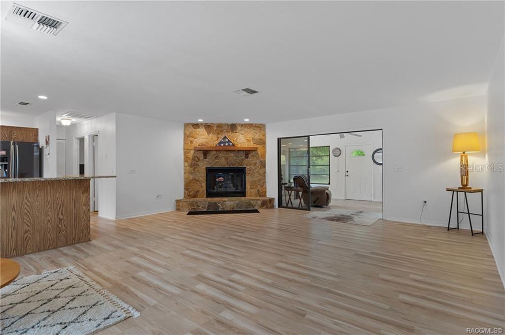 A living room features light wood-look flooring, a stone fireplace, and a sliding glass door — 9000 SW 206TH COURT ROAD, DUNNELLON, FL