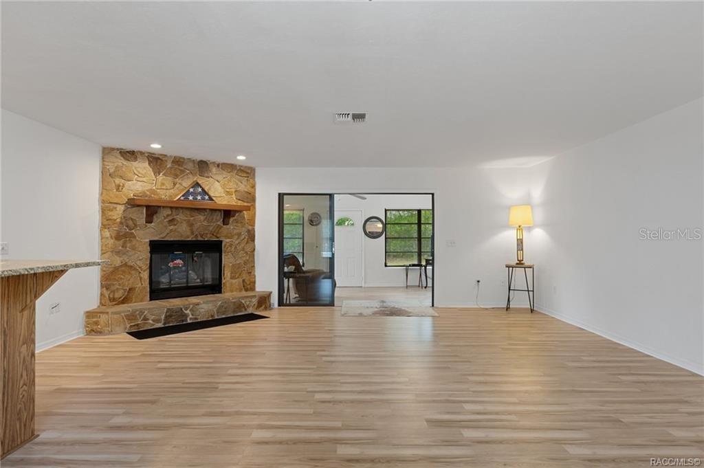 A living room features light wood-look flooring, a stone fireplace, and a sliding glass door — 9000 SW 206TH COURT ROAD, DUNNELLON, FL