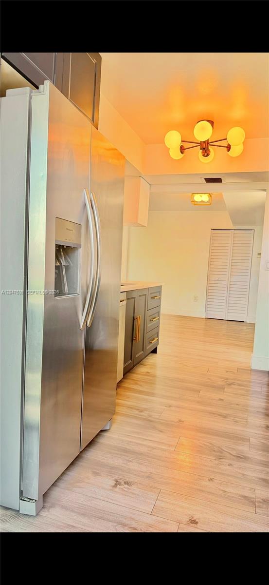 A stainless steel refrigerator stands in a kitchen with dark cabinets and light wood flooring — 8201 Byron Ave # 501, Miami Beach FL 33141, MIAMI BEACH, FL
