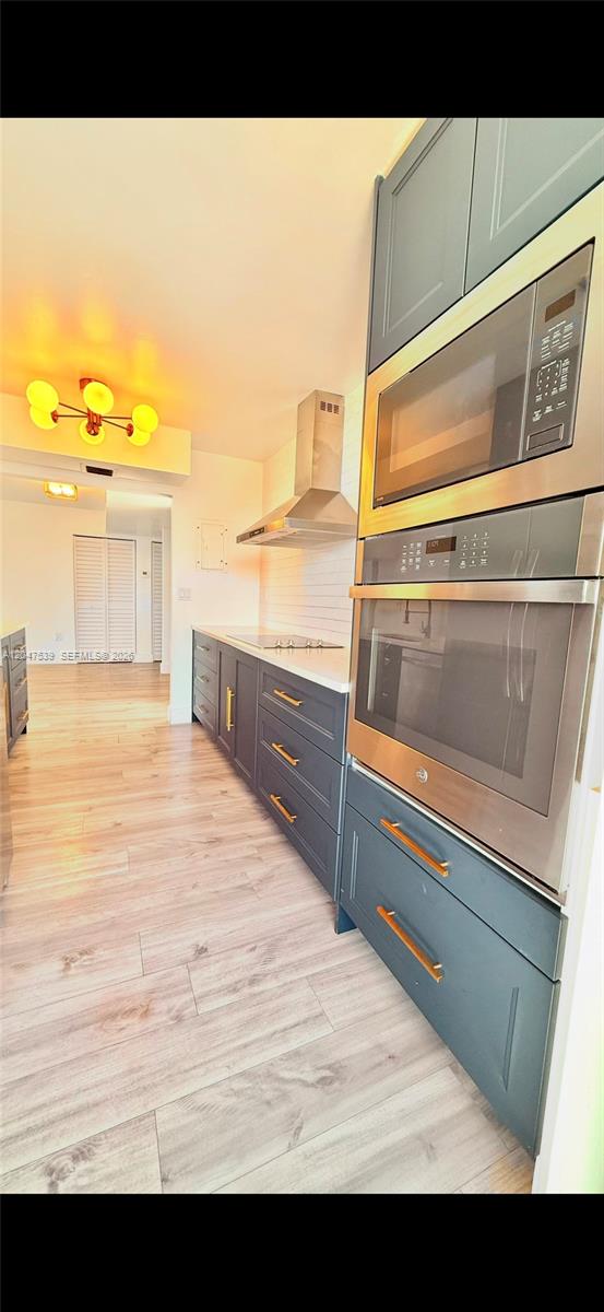 A kitchen features dark blue cabinetry, stainless steel appliances, and light wood-look flooring — 8201 Byron Ave # 501, Miami Beach FL 33141, MIAMI BEACH, FL