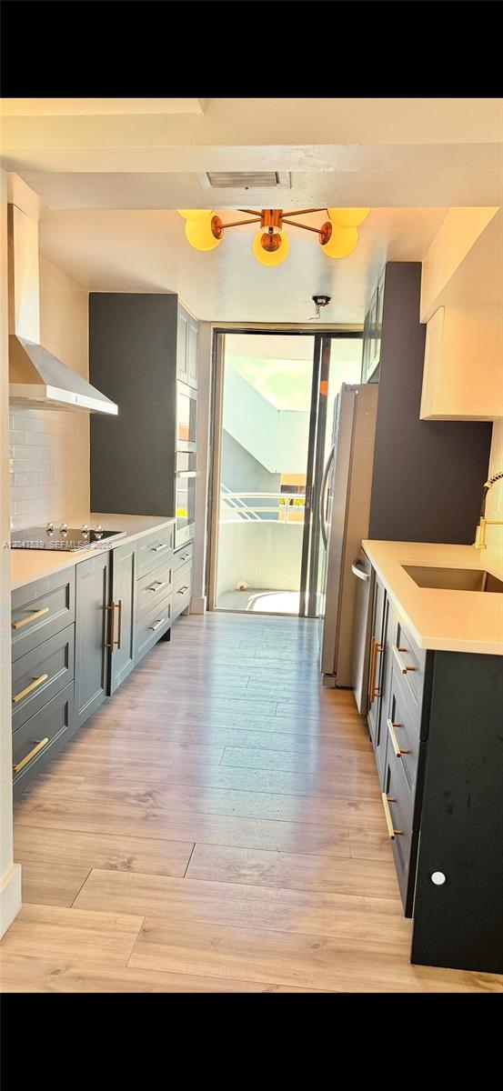A galley kitchen features dark gray cabinets, white countertops, stainless steel appliances, and a balcony — 8201 Byron Ave # 501, Miami Beach FL 33141, MIAMI BEACH, FL