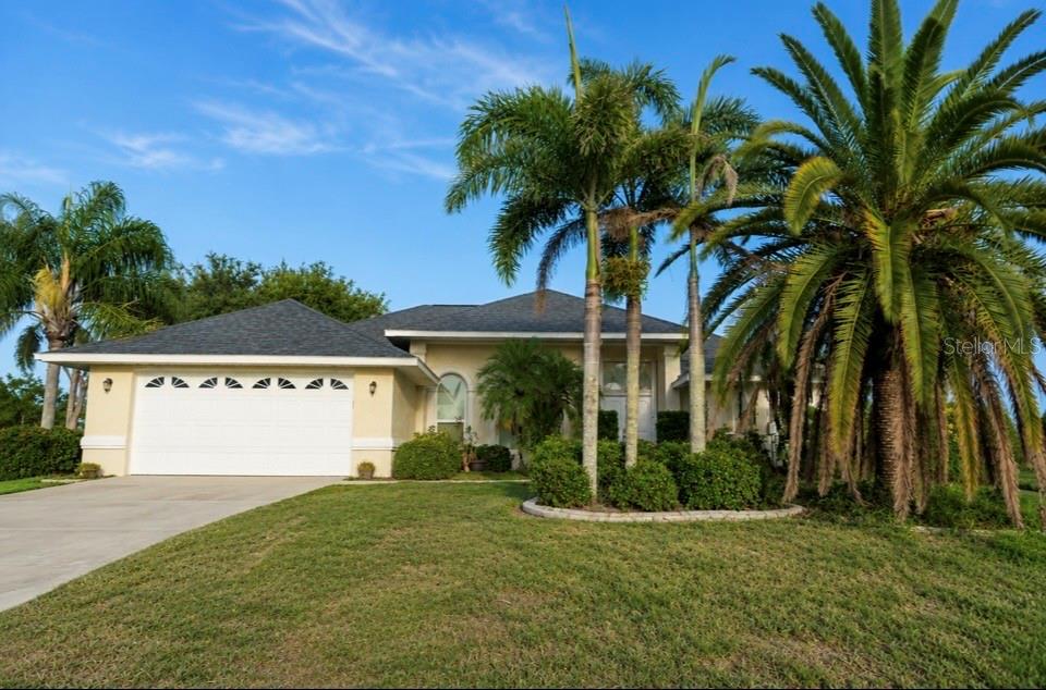 A single-story house with a white garage, beige stucco walls, and several palm trees — 10535 AZTEC ROAD, PORT CHARLOTTE, FL