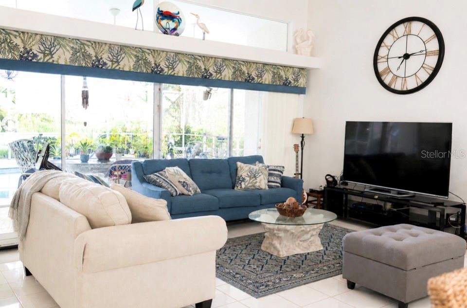A living room features a blue sofa, a cream loveseat, and a large wall clock — 10535 AZTEC ROAD, PORT CHARLOTTE, FL