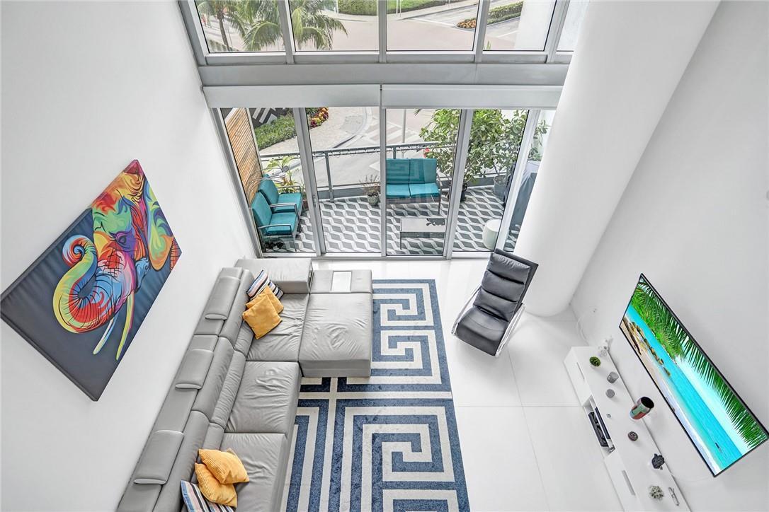 A modern kitchen with dark cabinetry and a white island opens to a living area — 90 SW 3rd Street, Miami FL 33130, MIAMI, FL
