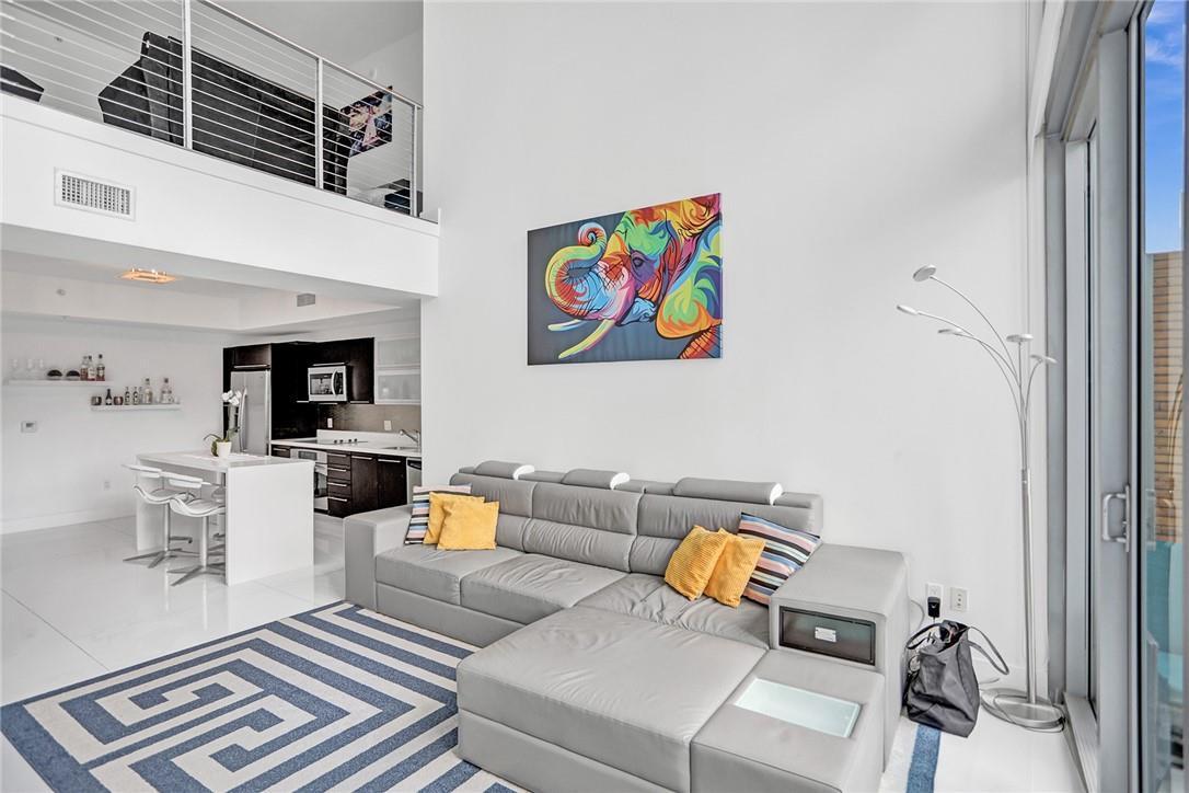 A modern living room with a grey sectional, patterned rug, and floor-to-ceiling windows overlooking city — 90 SW 3rd Street, Miami FL 33130, MIAMI, FL