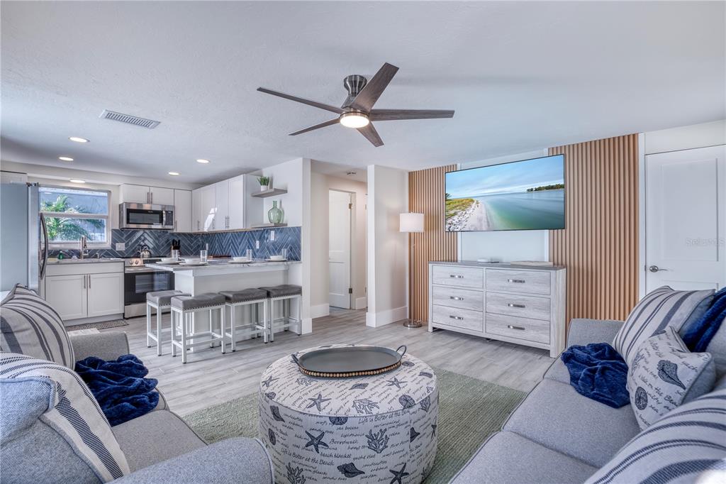 A living room with a kitchen island, wood-slat wall, and coastal-themed furniture — 3604 GULF DRIVE UNIT A and B, HOLMES BEACH, FL