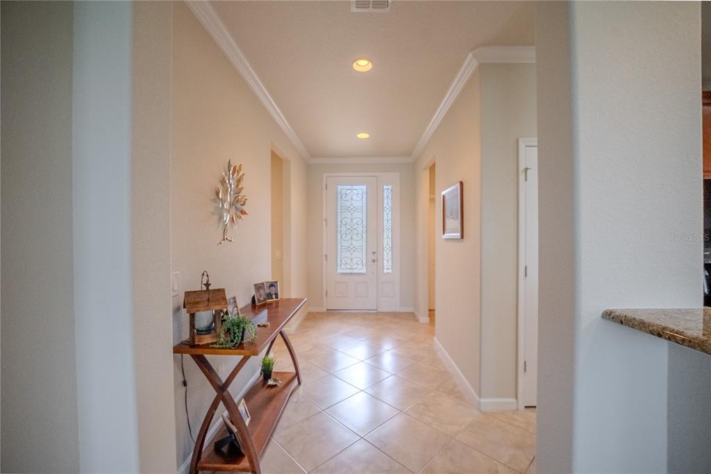 A brightly lit entryway features tiled floors, a wooden console table, and a glass-paneled front door — 9160 SW 70TH LOOP, OCALA, FL
