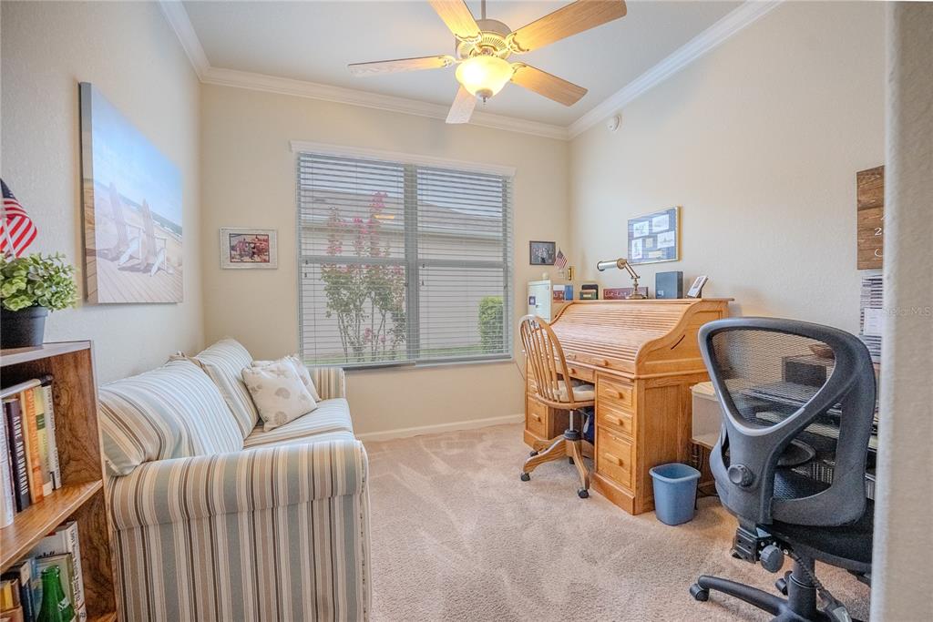 A home office features a striped sofa, a wooden roll-top desk, and a ceiling fan — 9160 SW 70TH LOOP, OCALA, FL