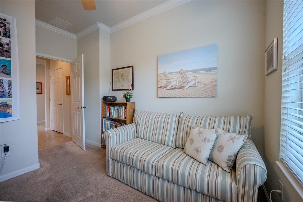 A room with a striped sofa, a small bookshelf, and a beach-themed wall art piece — 9160 SW 70TH LOOP, OCALA, FL