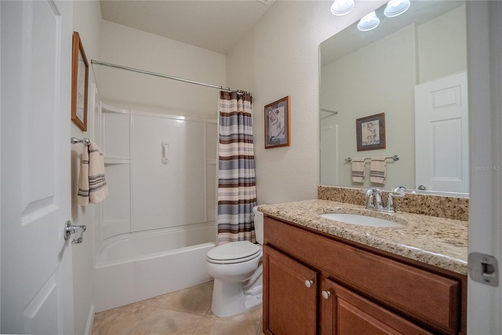 A bathroom features a granite-topped vanity, a white toilet, and a shower-tub combination — 9160 SW 70TH LOOP, OCALA, FL