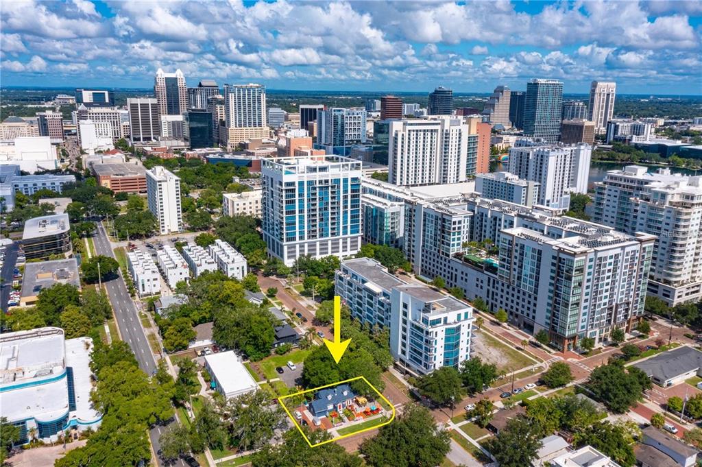 An aerial view shows a small house highlighted in yellow amidst a dense urban skyline — 300 S EOLA DRIVE, ORLANDO, FL