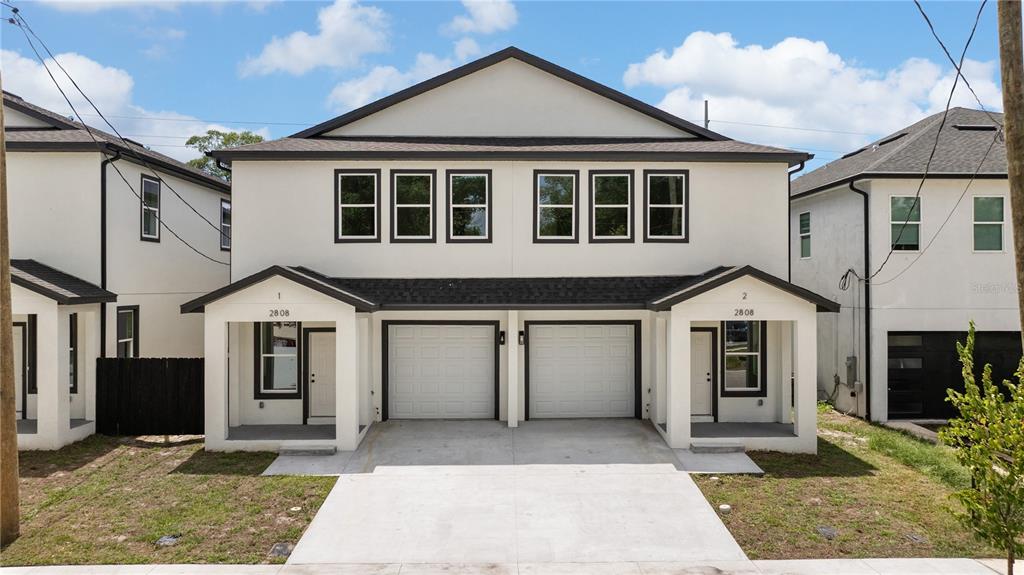 A two-story duplex with white stucco walls, dark trim, and two attached garages — 2806 N 29TH STREET UNIT 2, TAMPA, FL