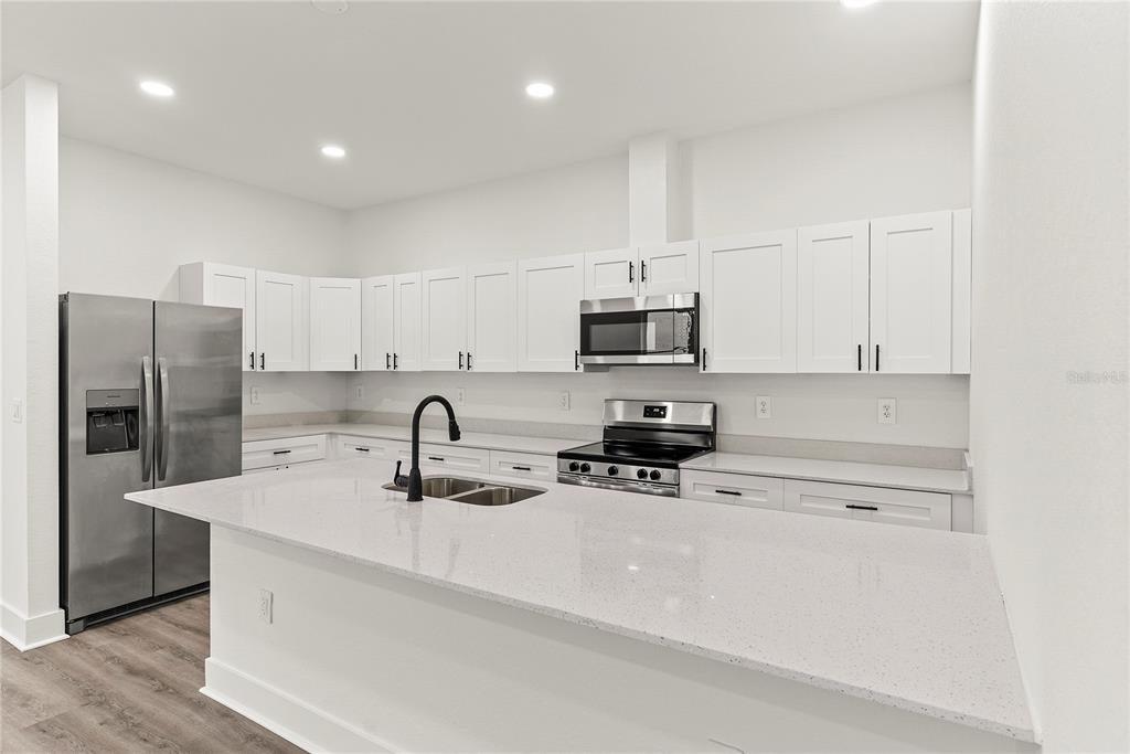 A modern kitchen features white cabinets, stainless steel appliances, and a large quartz island — 2806 N 29TH STREET UNIT 2, TAMPA, FL