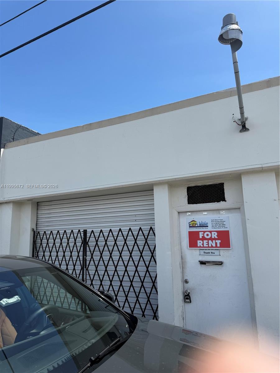An exterior view of a white building with a roll-up metal door and a door — 1017 N 20th Ave, Hollywood FL 33020, HOLLYWOOD, FL