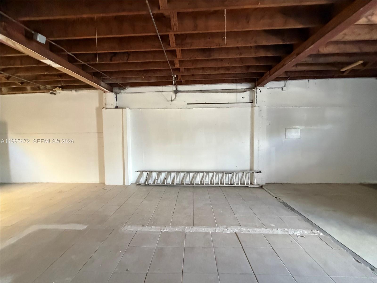 An unfinished commercial space features exposed wooden ceiling joists, white walls, and tiled flooring — 1017 N 20th Ave, Hollywood FL 33020, HOLLYWOOD, FL
