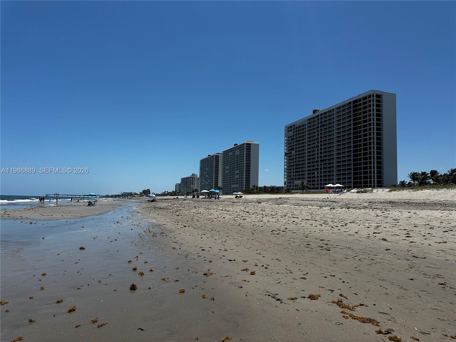 A sandy beach stretches toward several tall residential buildings under a clear blue sky — 2851 S Ocean Boulevard # V, Boca Raton FL 33432, BOCA RATON, FL