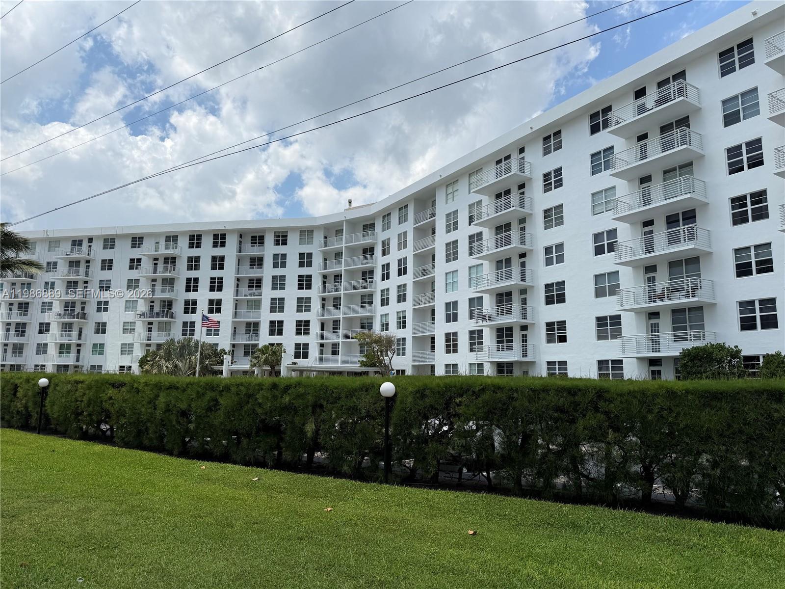 A multi-story white apartment building stands behind a manicured hedge and green lawn — 2851 S Ocean Boulevard # V, Boca Raton FL 33432, BOCA RATON, FL