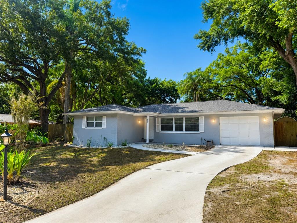 A single-story gray house with a white garage and a concrete driveway under large trees — 182 SUNWARD AVENUE, PALM HARBOR, FL