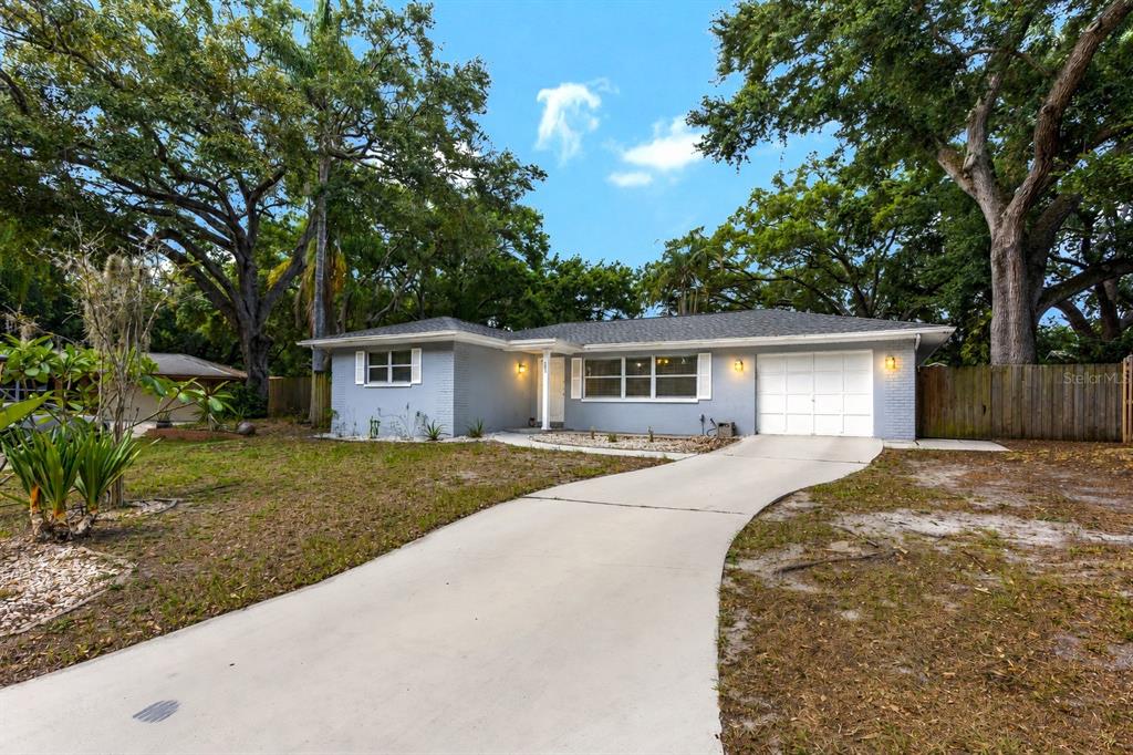 A light blue, single-story ranch-style house with a concrete driveway and mature trees — 182 SUNWARD AVENUE, PALM HARBOR, FL