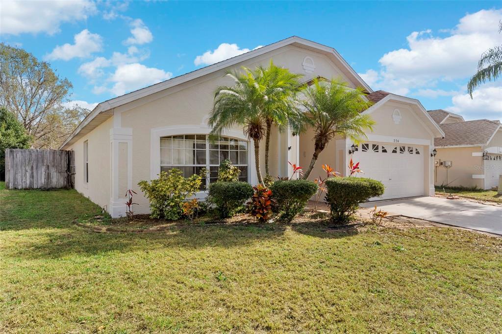 A single-story house with a beige stucco exterior, a two-car garage, and palm trees — 226 JESSAMINE DRIVE, DAVENPORT, FL