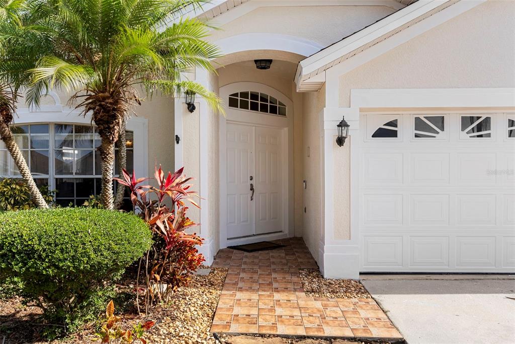 The exterior of a house features a tiled walkway leading to a white double front door — 226 JESSAMINE DRIVE, DAVENPORT, FL