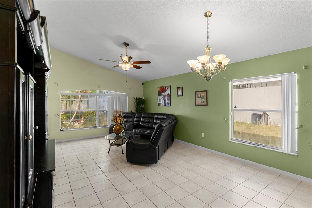 A living room features light green walls, tile flooring, a black sectional sofa, and two windows — 226 JESSAMINE DRIVE, DAVENPORT, FL