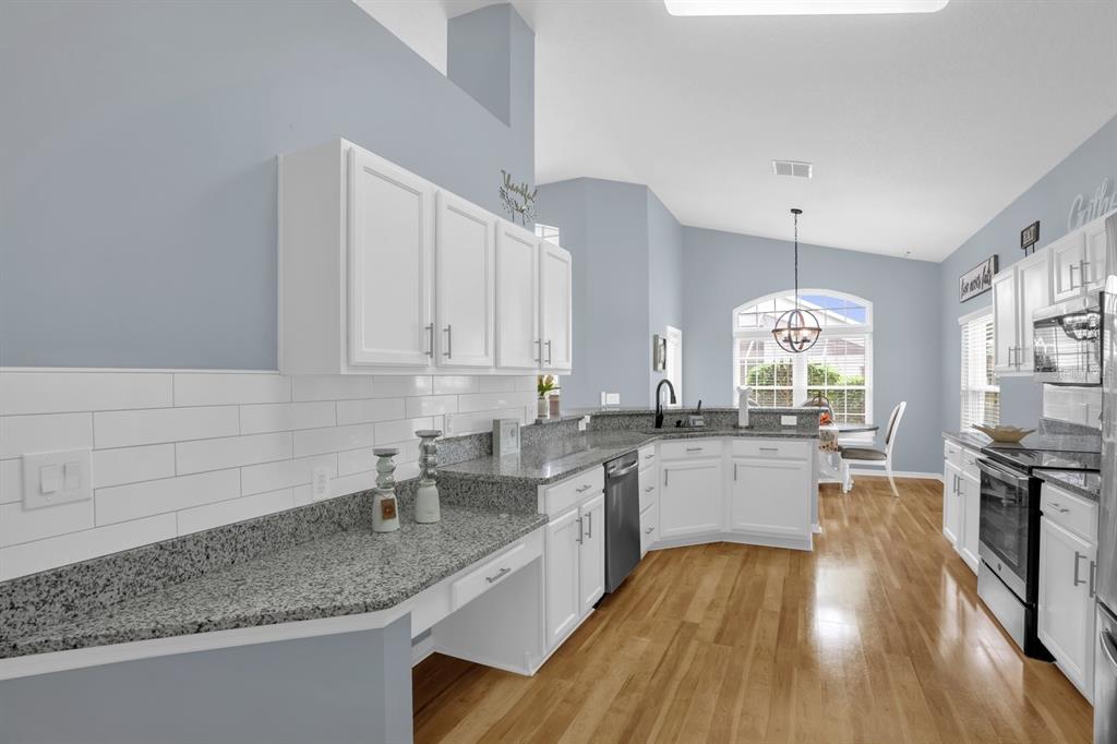 A kitchen with white cabinets, granite countertops, and light blue walls over hardwood floors — 116 FLEMING LANE, DAVENPORT, FL