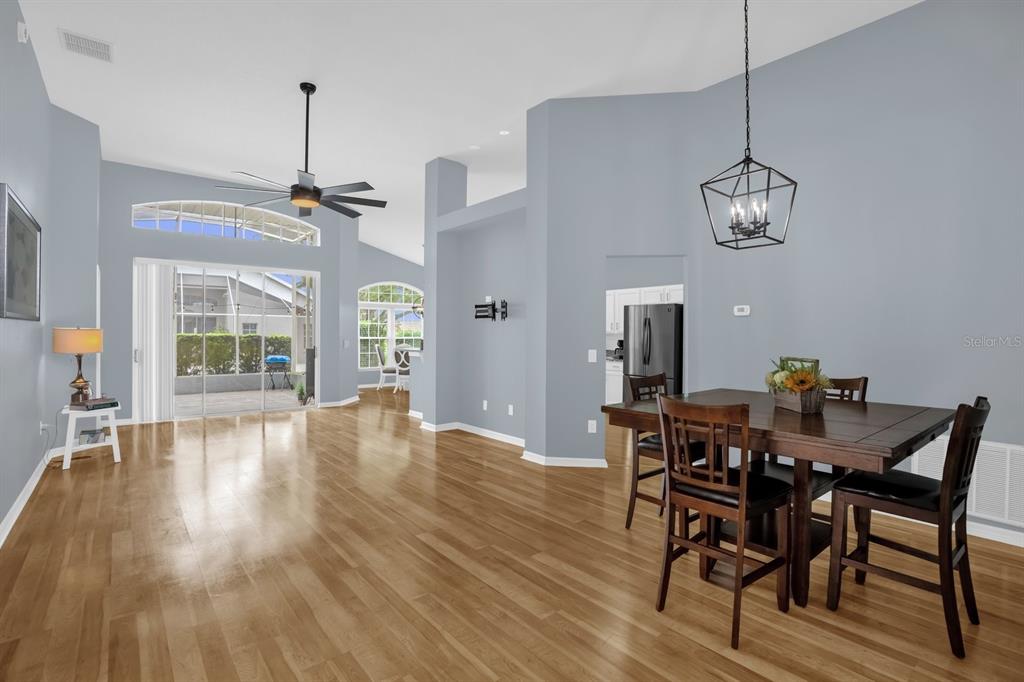 A dining area and living space with light blue walls, hardwood floors, and sliding doors — 116 FLEMING LANE, DAVENPORT, FL