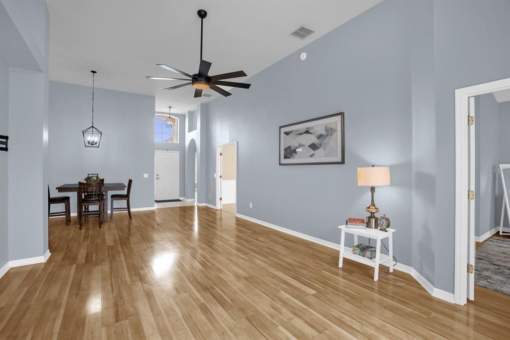 A spacious room with light blue walls, hardwood floors, a ceiling fan, and dining area — 116 FLEMING LANE, DAVENPORT, FL