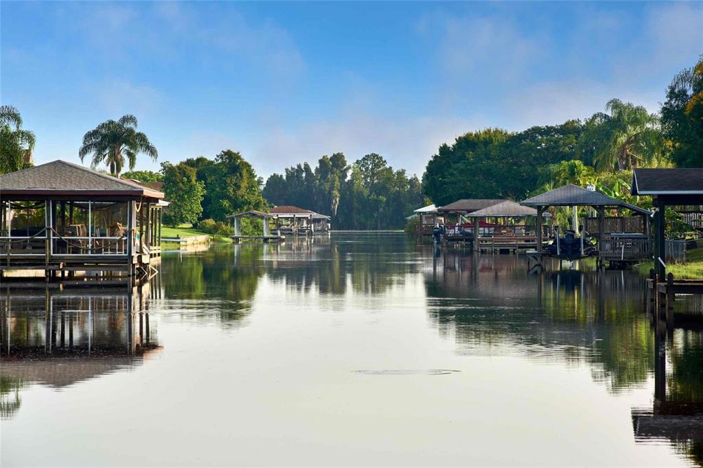 A calm canal lined with wooden boat docks and covered slips under a blue sky — 913 INDIAN LAKE DRIVE, INDIAN LAKE ESTATES, FL