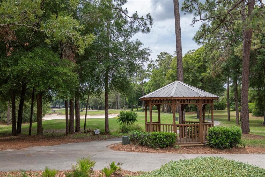 A wooden gazebo sits on a paved path overlooking a golf course with sand bunkers — 171 BIRCHMONT DRIVE, DELAND, FL