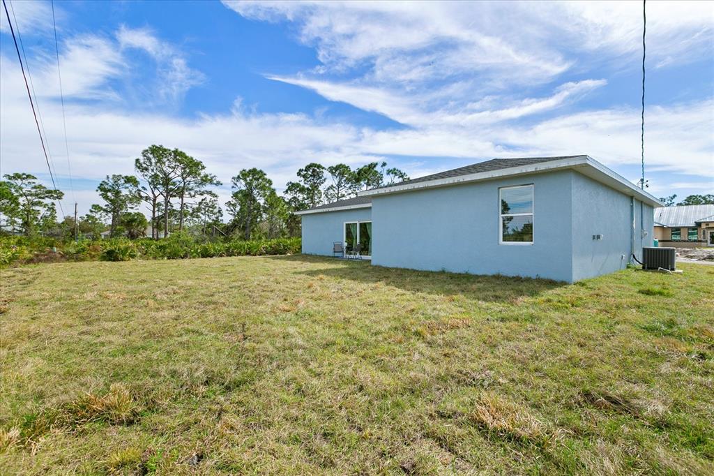 The exterior of a light blue house sits on a large, grassy lot — 18400 TULANE AVENUE, PORT CHARLOTTE, FL