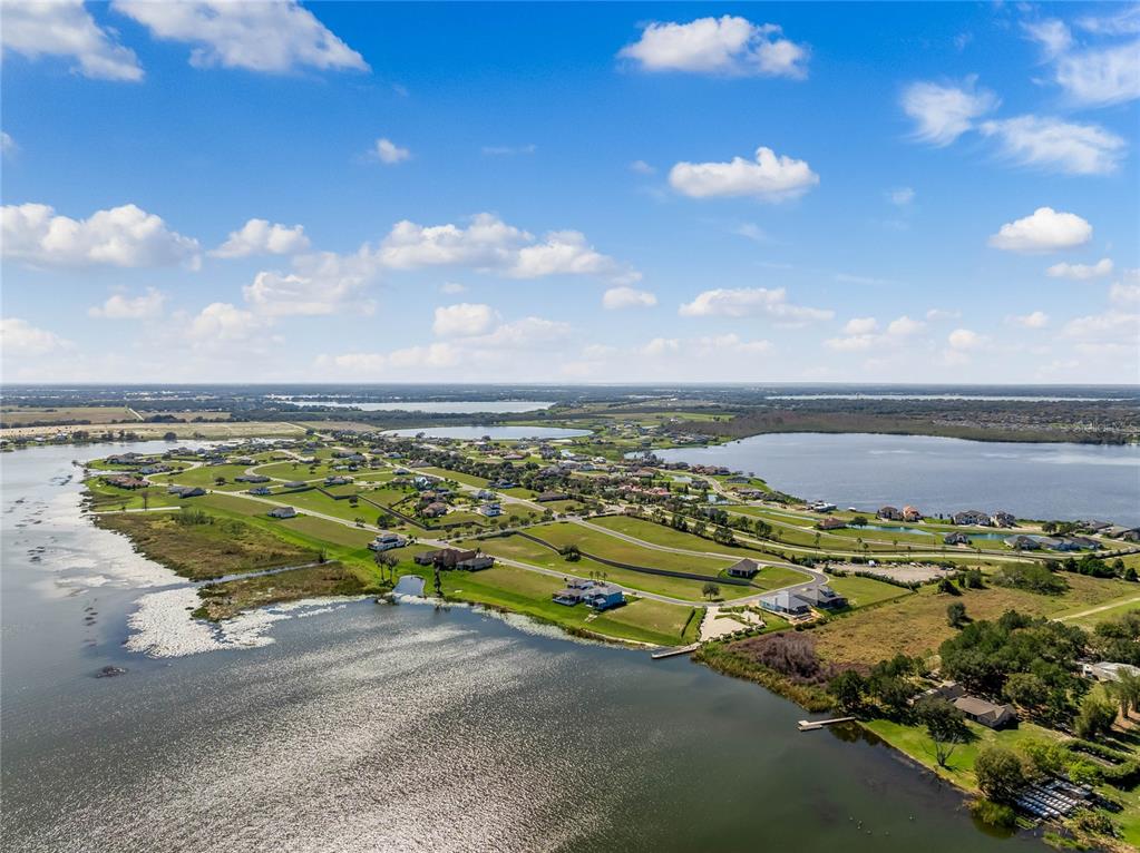An aerial view shows a residential community with houses, a central road, and multiple lakes — 535 ADAMS VIEW LANE, AUBURNDALE, FL