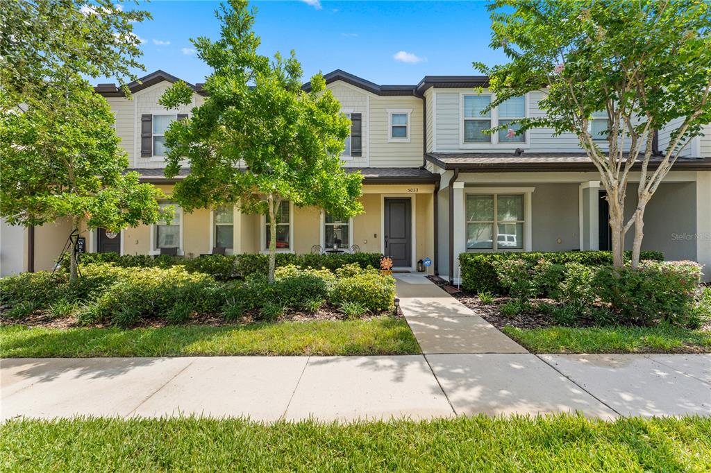 A two-story townhouse with a beige facade, dark shutters, and a front walkway — 5033 CASPIAN STREET, ST CLOUD, FL