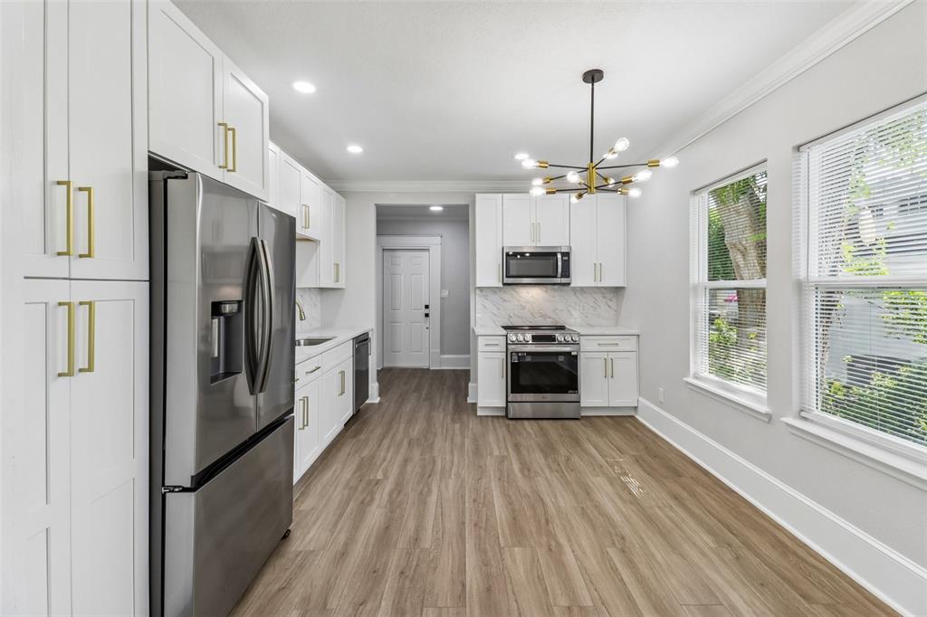 A modern kitchen features white cabinets, stainless steel appliances, and light wood-look flooring — 43 W MURIEL STREET, ORLANDO, FL