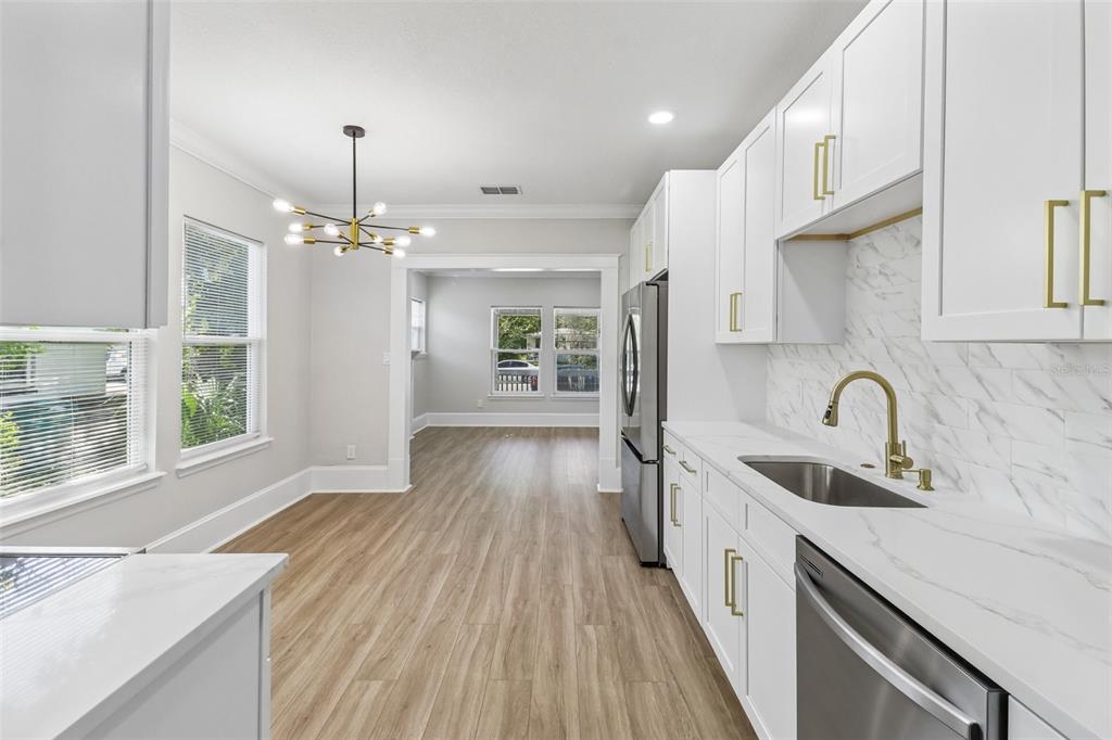 A modern kitchen features white cabinets, gold hardware, marble-look countertops, and light wood flooring — 43 W MURIEL STREET, ORLANDO, FL
