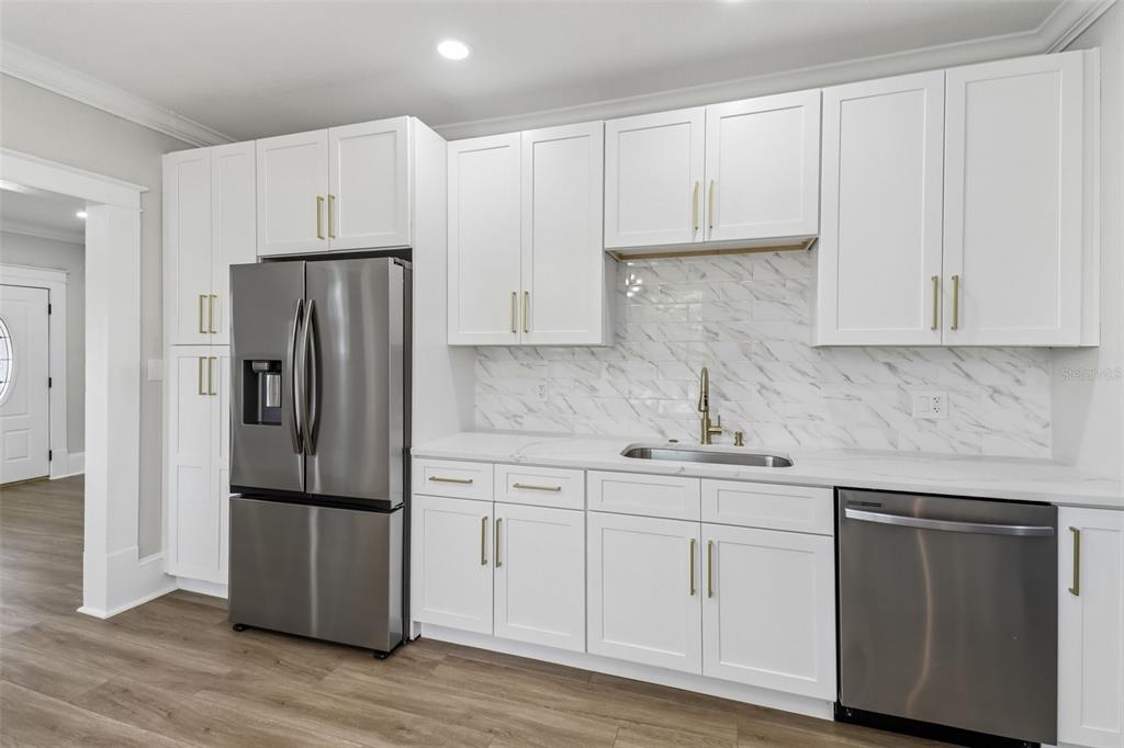 A modern kitchen features white shaker cabinets, stainless steel appliances, and a marble-patterned tile backsplash — 43 W MURIEL STREET, ORLANDO, FL