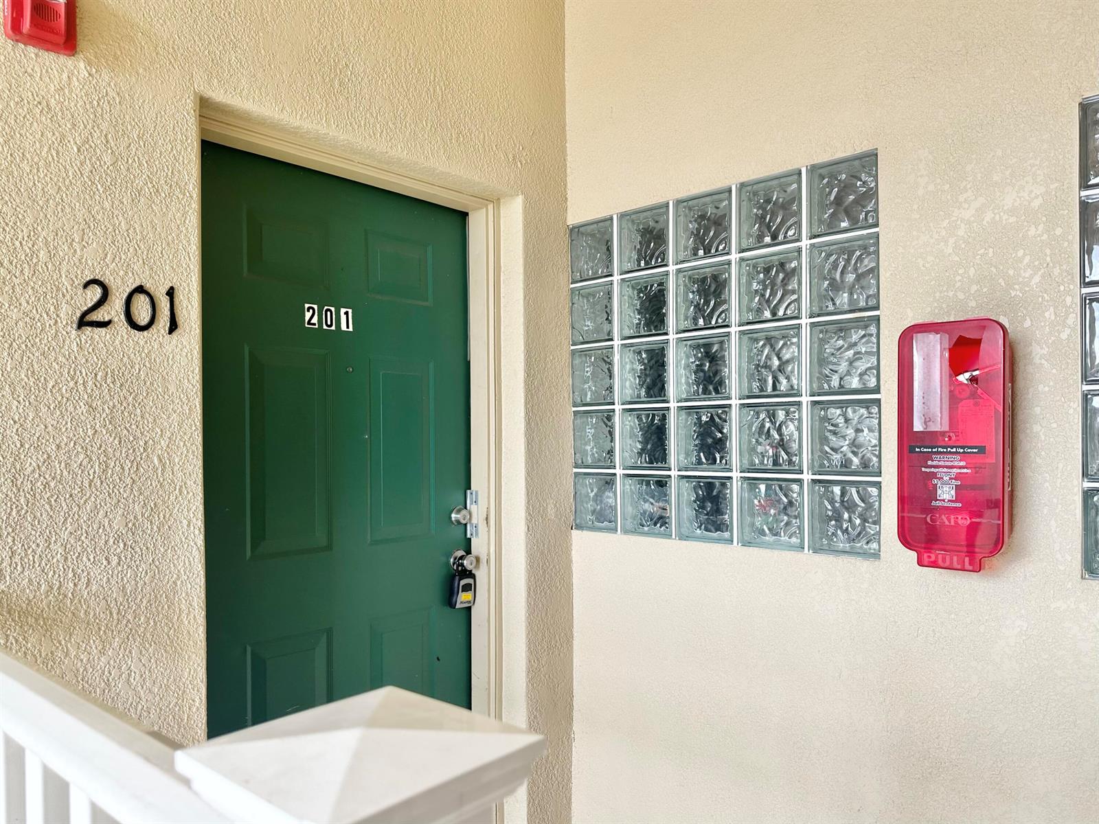 A green apartment door labeled 201 sits next to a glass block wall and alarm — 9604 Seadale Court # 201, Riverview FL 33578, RIVERVIEW, FL