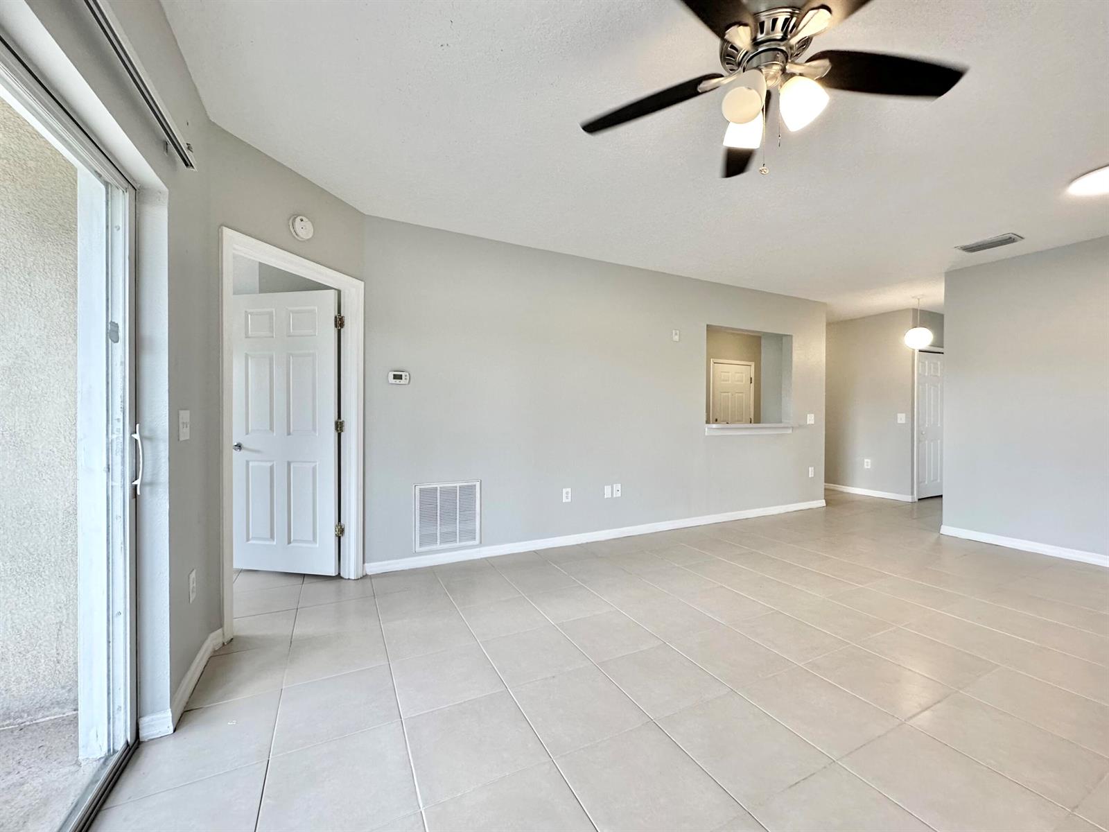An empty living room features light-colored tile flooring, gray walls, and a ceiling fan — 9604 Seadale Court # 201, Riverview FL 33578, RIVERVIEW, FL