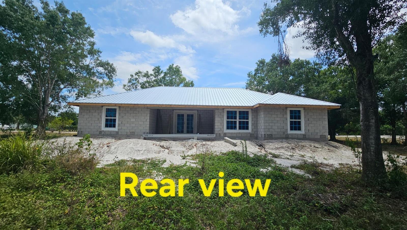 The rear exterior of a single-story concrete block house under construction with a metal roof — 3671 NW 16th Avenue, Okeechobee FL 34972, OKEECHOBEE, FL