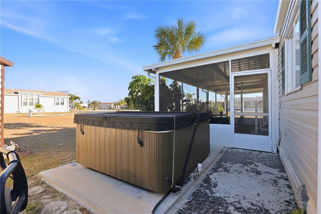 A hot tub sits on a concrete patio next to a screened-in porch — 1427 SANDERLING DRIVE, ENGLEWOOD, FL